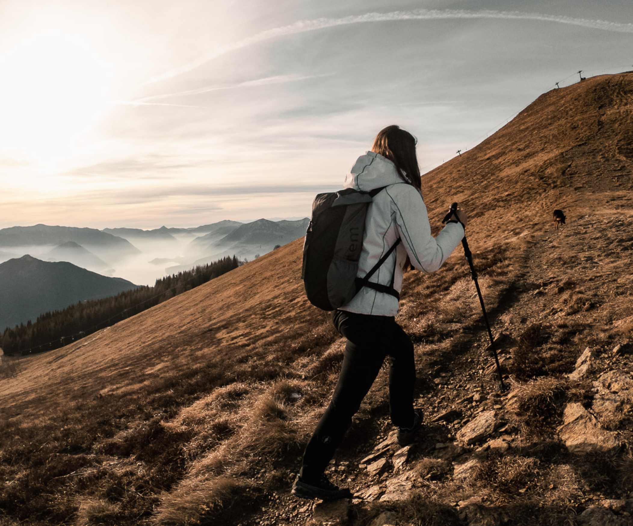 A Woman climbing a mountain with Trekking Poles.