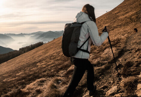 A woman climbing a mountain with Hiking Poles.