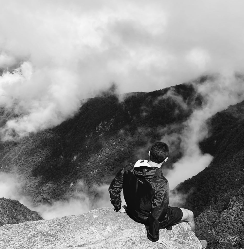 A man sitting on the edge of a mountain.