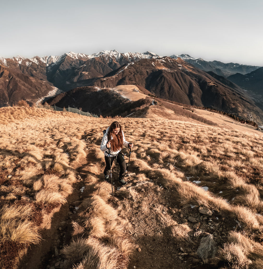 a woman climbing a mountain with Hiking Poles.